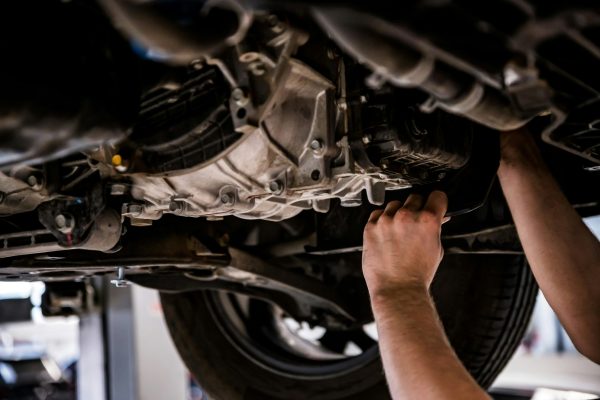 Close up of a mechanic hands repaires lifted car