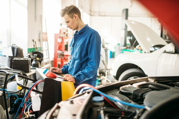 Mechanic checks air conditioning system in car